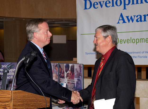 Lt. Gov. Jeff Kottkamp, left, and APD Director Jim DeBeaugrine shake hands while taking turns at the lectern during a Capitol news conference on Developmental Disabilities Day