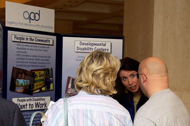 APD Communications Director Melanie Mowry Etters, facing the camera, assists visitors at the agency's booth