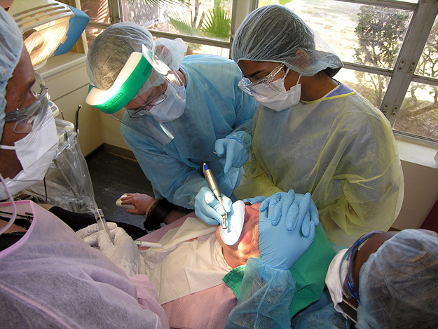 Dr. Timothy Garvey, DMD, second from left, removes tooth decay from a patient with developmental disabilities at Tacachale's dental clinic. He is assisted by University of Florida dental student Reema Phillips, third from left. Dental assistants Easie Styles, left, and Wanda Price, right, are critical to the dental care team's success