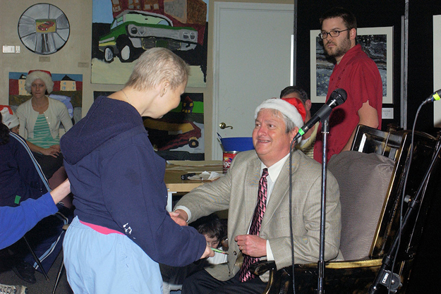 APD Director Jim DeBeaugrine, wearing the Santa hat, presents a holiday gift to a participant at Pyramid Studios in Tallahassee.