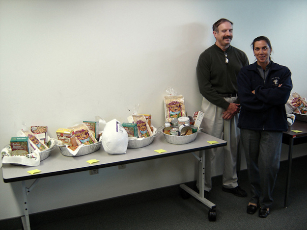 Dave Cassady and Cheryl Fleshman proudly display the Thanksgiving food baskets that APD's Area 12 Office donated to customers in need.