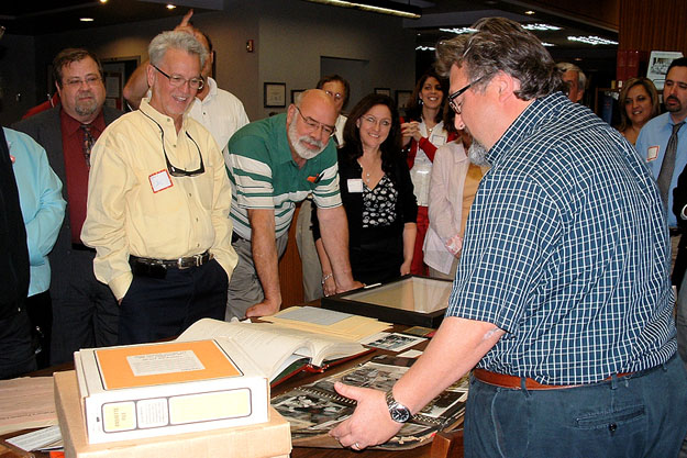 At the Florida Archives, Archivist Boyd Murphree, foreground, displays various historical documents, including a photo album from the Tallahassee Sunland Center