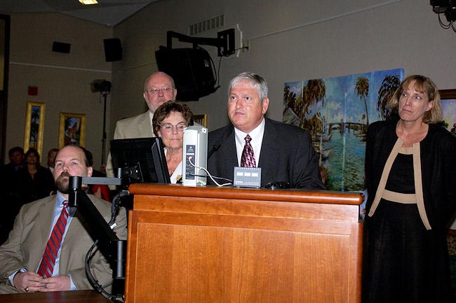 APD Director Jim DeBeaugrine addresses the governor and Cabinet to accept the ADA anniversary resolution. Behind him, from left, are Bryan Vaughan, executive director of the Governor's Commission on Disabilities; Bill Palmer, director of the Division of Vocational Rehabilitation; Susanne Homant, president and CEO of the Able Trust; and Debra Dowds, executive director of the Florida Developmental Disabilities Council
