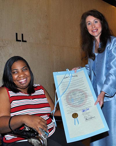Swanzetta Green, left, and APD Communications Director Melanie Mowry Etters pose with the resolution that declares October as Disability Employment Awareness Month in Florida