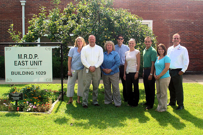 Legislative staff members and APD employees pose for a photo while touring the agency's Mentally Retarded Defendant Program (MRDP) in Chattahoochee. From left, APD Legislative Affairs Director Logan McFadden; Ralph Perkins, House Health Care Appropriations Committee; Sharon Bradford, Senate Committee on Health and Human Services Appropriations; Chris Schoonover, House Health Care Services Policy Committee; Amanda Hannson, Senate Committee on Children, Families and Elder Affairs; Jared Torres, APD Legislative Affairs; Danielle Scoggins, APD Legislative Affairs; and MRDP Superintendent Charles Ball