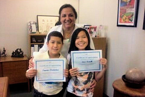 Area 11 Administrator Evelyn Alvarez presents young Francisco Orochena, left, and Laura Cardello with certificates for participating in 