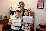 Area 11 Administrator Evelyn Alvarez presents young Francisco Orochena, left, and Laura Cardello with certificates for participating in "Take Our Daughters and Sons to Work Day."