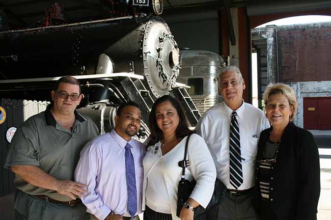 APD Director Barbara Palmer visits customer Duane Chin Loy at Gold Coast Railroad Museum in South Miami-Dade, where an internship led Loy to a job. From left, Maclyn Black, supported living coach; Loy; Evelyn Alvarez, APD Southern Region manager; Michael Cardello, Southern Region community relations coordinator; and Palmer. 