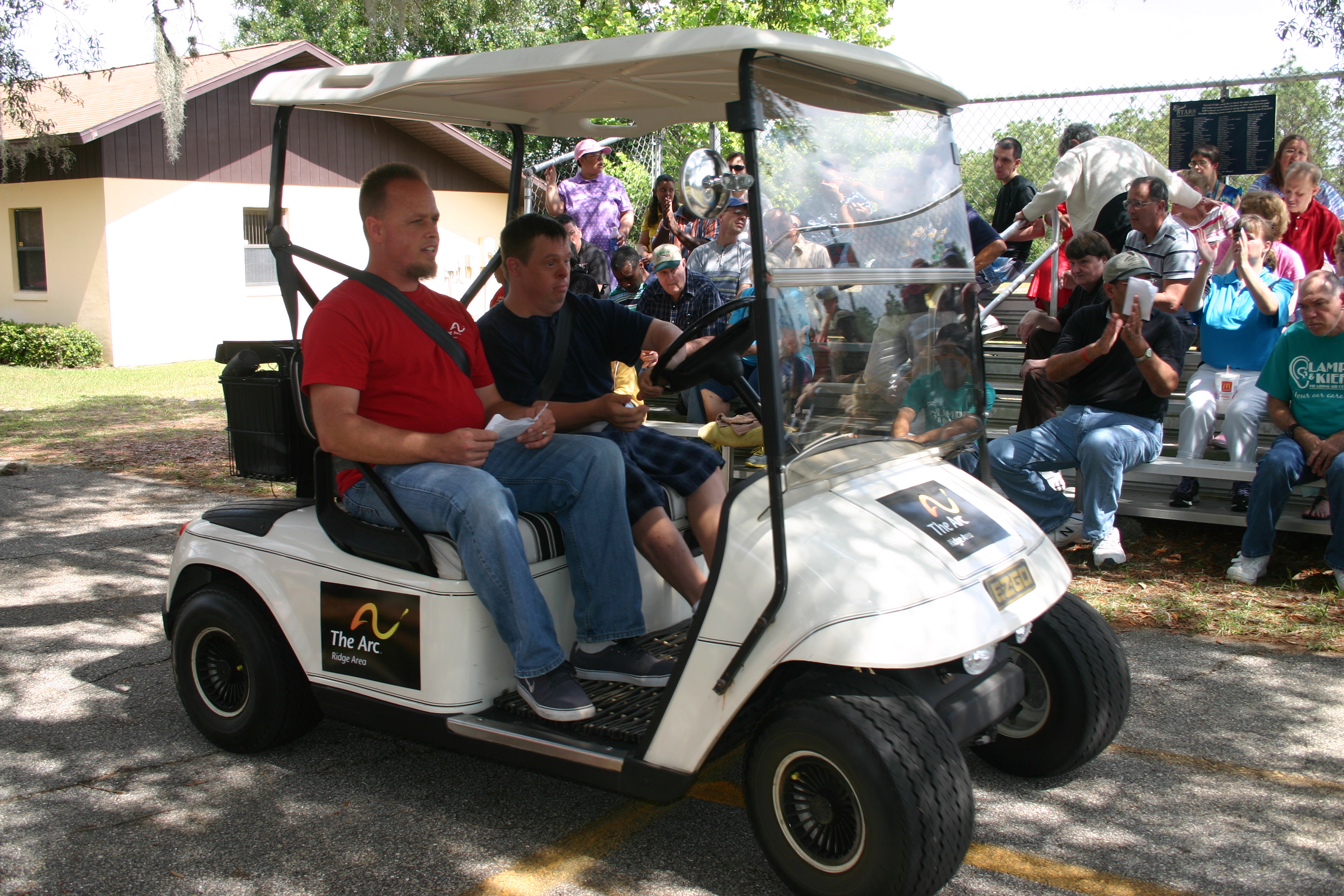 Ridge Area Arc consumer Gerald Bass focuses on the road ahead as he takes off to drive the golf cart. Arc staff member Chris Perkins rides along for supervision during the demonstration for the graduation.