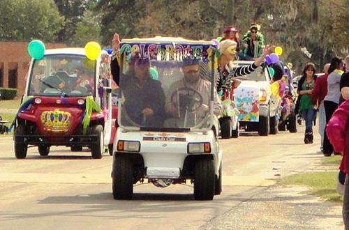 Superintendent Bryan Vaughan, Assistant Superintendent Darlene See, and Executive Assistant Beth Basford lead Sunland's Mardi Gras parade, showering the crowd with colorful beads.